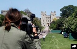 FILE - A camera woman films the Long Walk toward Windsor Castle in Windsor, England, May 15, 2018.