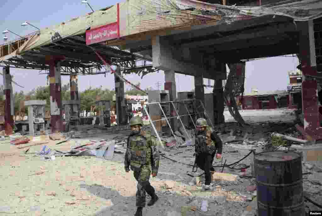 Forces loyal to Syria&#39;s President Bashar al-Assad walk near a damaged gas station near the main highway leading Aleppo to Raqqa, Nov. 11, 2013.