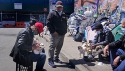 Sotero Cirilo, left, and Alfredo Martinez, second from left, relax in front of the tents where they have been sleeping in the Queens borough of New York, Tuesday, April 13, 2021.