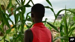 FILE - Eliza, 17, who at age 13 was forced by her father to marry a 35-year-old man from their village in exchange for 50 cattle, stands next to crops in a courtyard in the town of Rumbek, South Sudan, July 30, 2017.