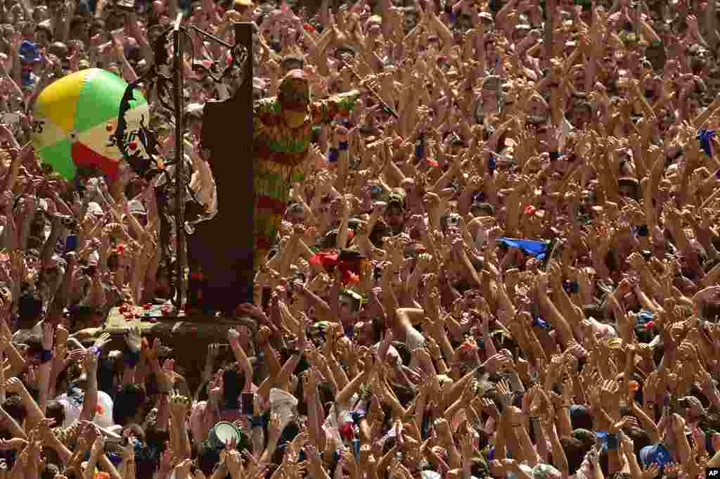 A hooded man with a colorful outfit known as the 'Cipotegato' acknowledges the crowd after running through the streets of Tarazona, Spain.
