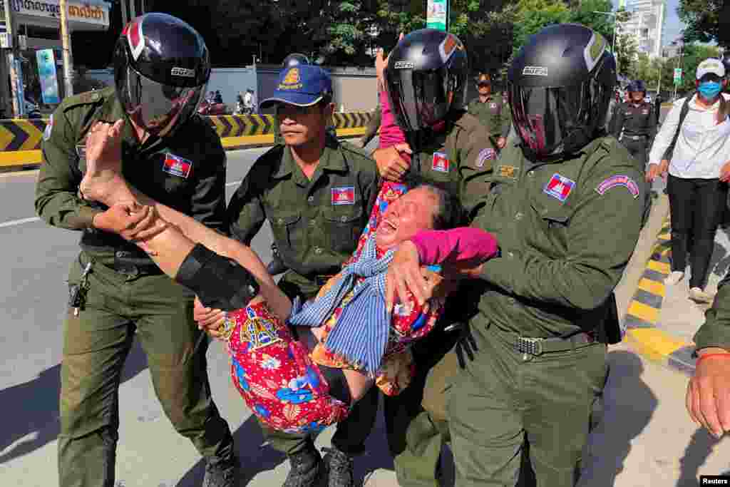 A woman is carried by police officers after security guards broke up a small protest near the Chinese embassy opposing alleged plans to boost Beijing&#39;s military presence in the country, in Phnom Penh, Cambodia.