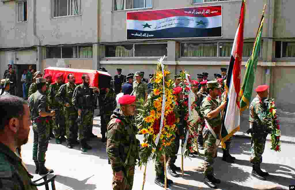 Tentara Suriah membawa peti mati komandan Pasukan Pertahanan Nasional pro-pemerintah, Hilal Assad, dalam pemakamannya di sebuah rumah sakit di propinsi Latakia, 24 Maret 2014.