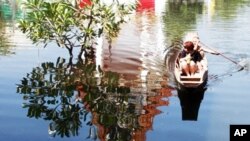 A man rows his passenger on a boat past the shadow of the flooded Chatkaew Chongkolnee temple in Bangkok, Thailand, November 1, 2011.