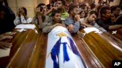 FILE - Relatives of Coptic Christians who were killed during a bus attack surround their coffins during their funeral service at Abu Garnous Cathedral in Minya, Egypt, May 17, 2017. 