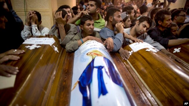 FILE - Relatives of Coptic Christians who were killed during a bus attack, surround their coffins, during their funeral service, at Abu Garnous Cathedral in Minya, Egypt, May 17, 2017. The Libya connection in the Manchester concert bombing and Friday’s attack on Christians in Egypt has shone a light on the threat posed by militant Islamic groups that have taken advantage of lawlessness in the troubled North African nation to put down roots, recruit fighters and export jihadists to cause death and carnage elsewhere. 