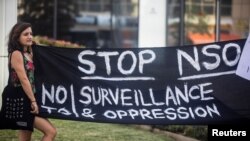 FILE - A protester holds a banner during a protest attended by about a dozen people outside the offices of the Israeli cyber firm NSO Group in Herzliya near Tel Aviv, Israel, July 25, 2021.