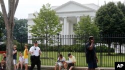 FILE - A Uniformed Division Secret Service police officer patrols with a dog as visitors walk on Pennsylvania Avenue in front of the White House in Washington, July 9, 2014.