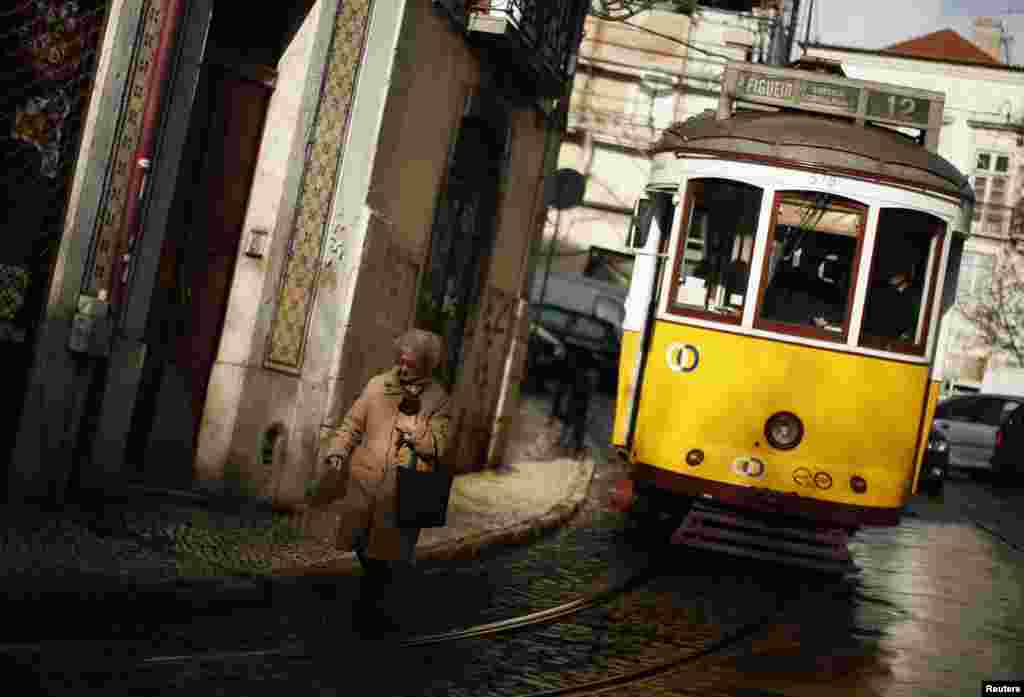 A woman walks near a tram at the Alfama neighborhood in Lisbon, Portugal.