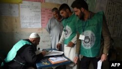 This photo taken on April 14, 2018, shows Afghan employees of the Independent Election Commission registering a resident at a voter registration center for the upcoming parliamentary and district council elections in Kabul.