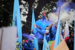 Para buruh merayakan "kemenangan" mereka setelah hakim di Mahkamah Konstitusi membacakan putusan uji materi UU Cipta Kerja agar ditinjau ulang oleh DPR dan Pemerintah Indonesia, Jakarta, 25 November 2021. (Foto: Indra Yoga/VOA)