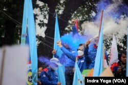 Para buruh merayakan "kemenangan" mereka setelah hakim di Mahkamah Konstitusi membacakan putusan uji materi UU Cipta Kerja agar ditinjau ulang oleh DPR dan Pemerintah Indonesia, Jakarta, 25 November 2021. (Foto: Indra Yoga/VOA)