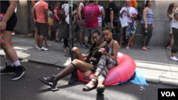 Miami (left) and Nill wait their turn on 40th street, before joining the pride march. More than 32,000 marchers and 400 groups participated. (R. Taylor/VOA)