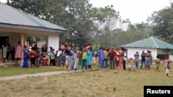 FILE - A still image taken from a video shot on Dec. 9, 2017, shows Cameroonian refugees standing outside a center in Agbokim Waterfalls village, Nigeria, near the country's border with Cameroon.