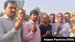 Voters emerge from a polling station in Western Uttar Pradesh holding up their fingers which get marked with ink after they cast ballots. 