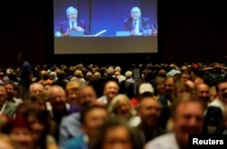 Warren Buffett, left, CEO of Berkshire Hathaway Inc., and Charlie Munger, vice chairman of Berkshire are seen on a screen at the company's annual meeting in Omaha, Neb., May 5, 2018.