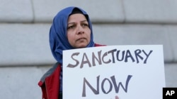 Warga bernama Moina Shaiq berpartisipasi dalam protes melawan kebijakan Donald Trump soal imigrasi, di luar Balai Kota San Francisco (25/1). (AP/Jeff Chiu)