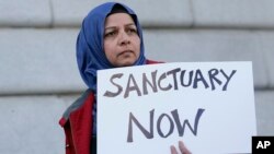 FILE - Moina Shaiq holds a sign at a rally outside of City Hall in San Francisco, Jan. 25, 2017.