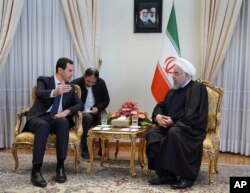 In this photo released by the Syrian official news agency SANA, Syrian President Bashar al-Assad, left, speaks with Iranian President Hassan Rouhani during their meeting in Tehran, Syria, Feb. 25, 2019.