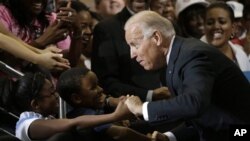 Vice President Joe Biden greets Lawrence Smith, 8, and Madison King, 9, both of Van Buren Township, Michigan, during a campaign stop at Renaissance High School in Detroit, Michigan, August 22, 2012.