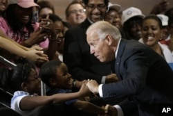 FILE - Vice President Joe Biden greets Lawrence Smith, 8, and Madison King, 9, both of Van Buren Township, Michigan, during a campaign stop at Renaissance High School in Detroit, Aug. 22, 2012.
