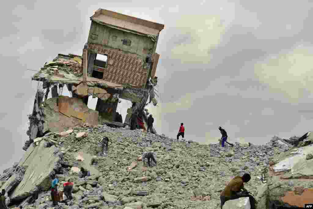 People salvage construction material, at a demolition site with precariously tilting rubble after government bulldozers knocked down a mall said to be illegal for having been built on a river bed in the Kenyan capital, Nairobi.