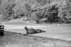 This June 6, 1966 file photo, shows civil rights activist James Meredith grimacing in pain as he pulls himself across Highway 51 after being shot in Hernando, Miss., during his March Against Fear. (AP Photo/Jack Thornell, File)
