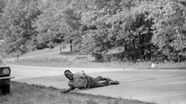 This June 6, 1966 file photo, shows civil rights activist James Meredith grimacing in pain as he pulls himself across Highway 51 after being shot in Hernando, Miss., during his March Against Fear. (AP Photo/Jack Thornell, File)