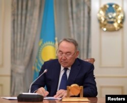 FILE - Kazakhstan's President Nursultan Nazarbayev writes during a televised address to announce his resignation, in Astana, Kazakhstan, March 19, 2019.