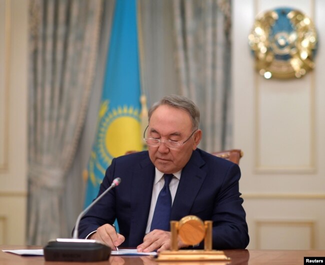 FILE - Kazakhstan's President Nursultan Nazarbayev writes during a televised address to announce his resignation, in Astana, Kazakhstan, March 19, 2019.