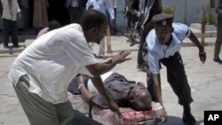 Somalis carry a wounded man away on a stretcher after the blast at the Somali National Theater in Mogadishu, Somalia, April 4, 2012.