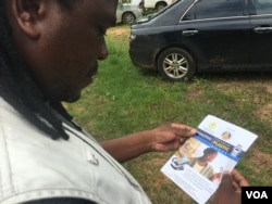 A man reading a Reserve Bank of Zimbabwe flyer promoting the use of plastic money to ease the country's over-a-year problem of cash shortages, Gokwe, Zimbabwe, Jan. 31, 2017. (S. Mhofu/VOA)