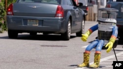 FILE- A car drives by HitchBOT, a hitchhiking robot in Marblehead, Massachusetts, July 17, 2015.