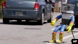 FILE- A car drives by HitchBOT, a hitchhiking robot in Marblehead, Massachusetts, July 17, 2015.