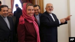 Iranian Foreign Minister Mohammad Javad Zarif, right, gestures while he makes way with European Union foreign policy chief Federica Mogherini, center, for a round of talks, in Tehran, Iran, July 28, 2015.