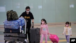 Passengers wear face masks after arriving at Hong Kong airport, Monday, March 23, 2020. Hong Kong will close its border to non-residents for 14 days starting from Wednesday, its chief executive announced on Monday after the number of coronavirus patients 
