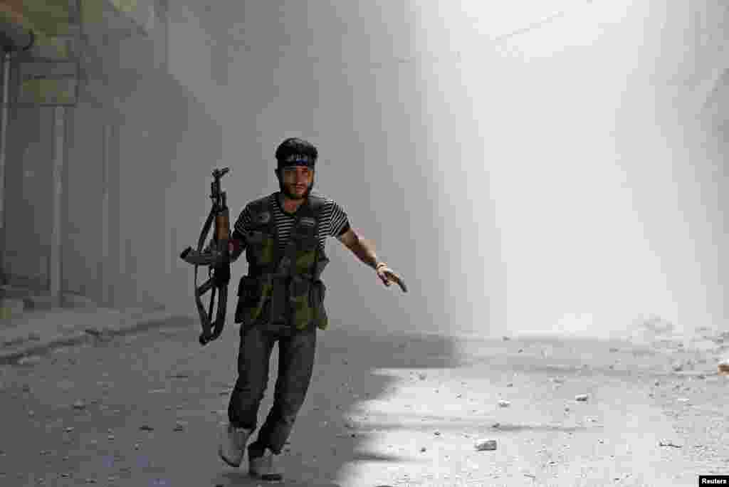 8月5日，在阿勒颇城的萨拉赫丁区战火中，一名反政府的叙利亚自由军躲避政府军的坦克炮 弹射击