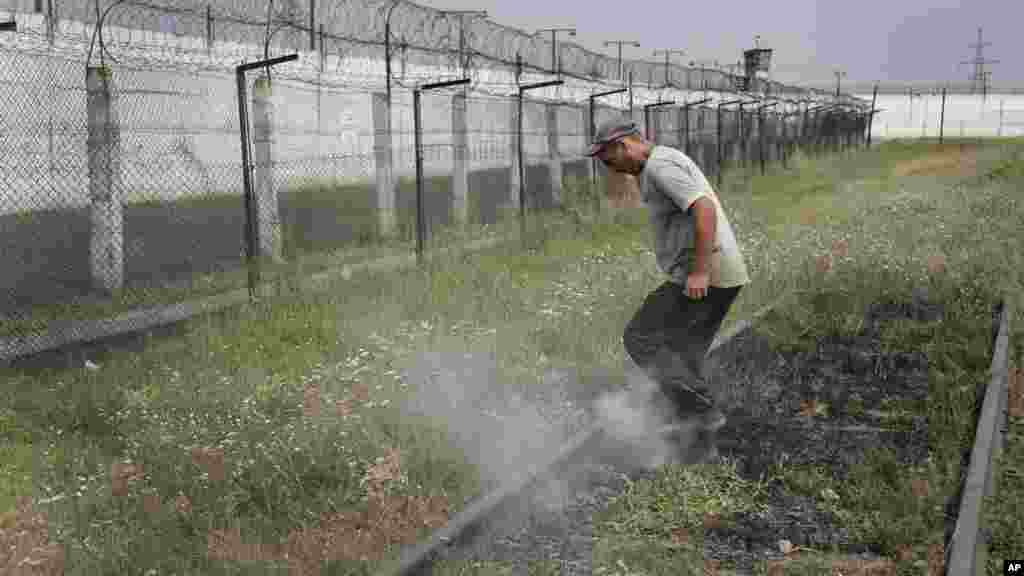 A prisoner tramples smoldering grass in a high-security facility after shelling in Donetsk, eastern Ukraine, Aug. 11, 2014. 