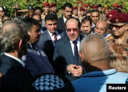 Iraq's Prime Minister Nouri al-Maliki, center, attends the funeral ceremony of Major General Negm Abdullah Ali, commander of the army's sixth division, at the Defense Ministry in Baghdad, July 7, 2014.
