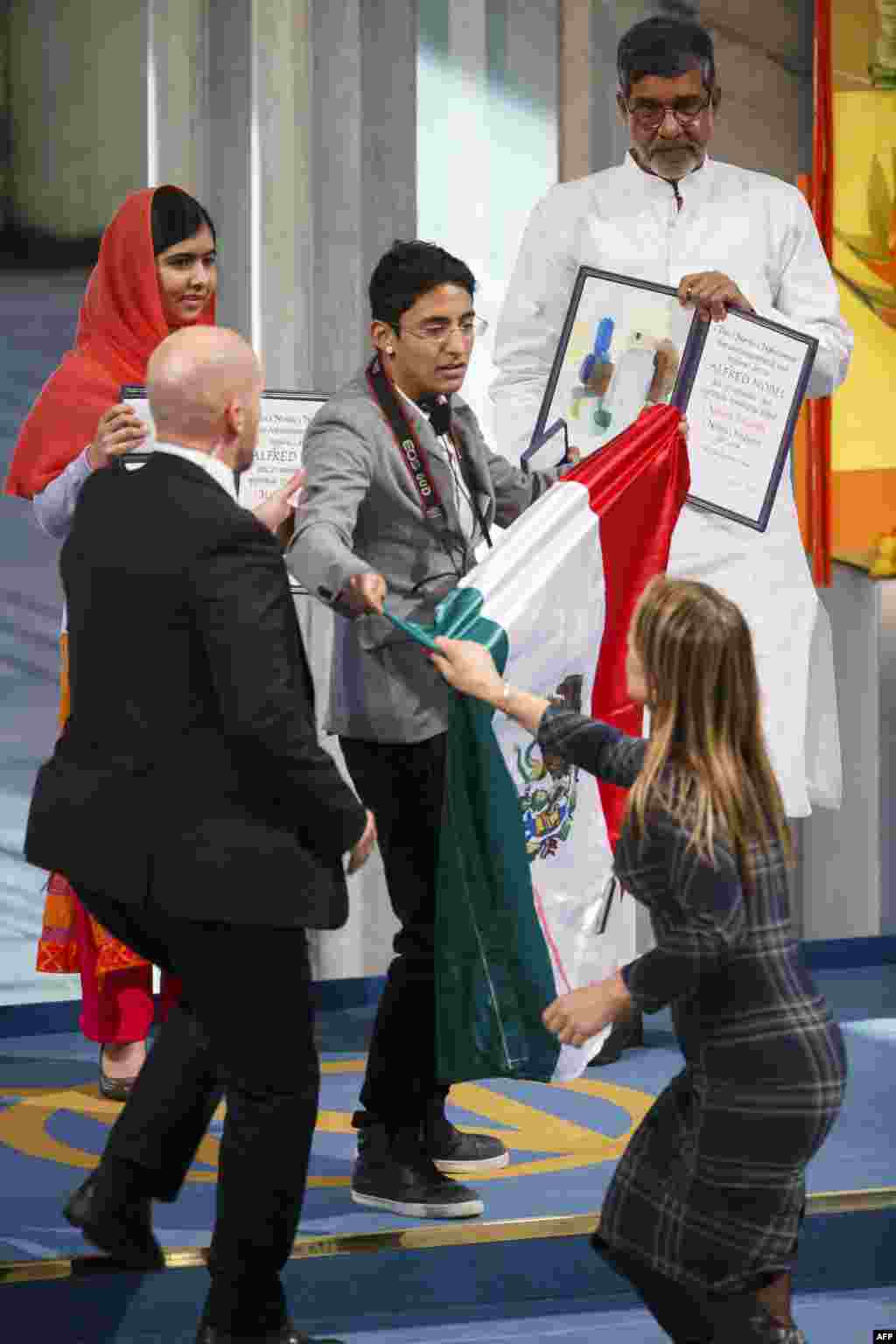 Nobel Peace Prize laureates Malala Yousafzai (left) and Kailash Satyarthi look on as security officers lead away a man displaying a flag of Mexico during the Nobel Peace Prize awards ceremony at the City Hall in Oslo, Norway.