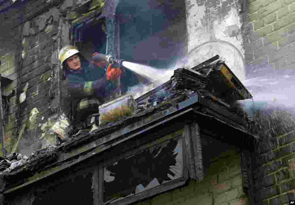 A firefighter sprays water at an apartment building damaged by shelling in the town of Donetsk, eastern Ukraine, Sept. 17, 2014.