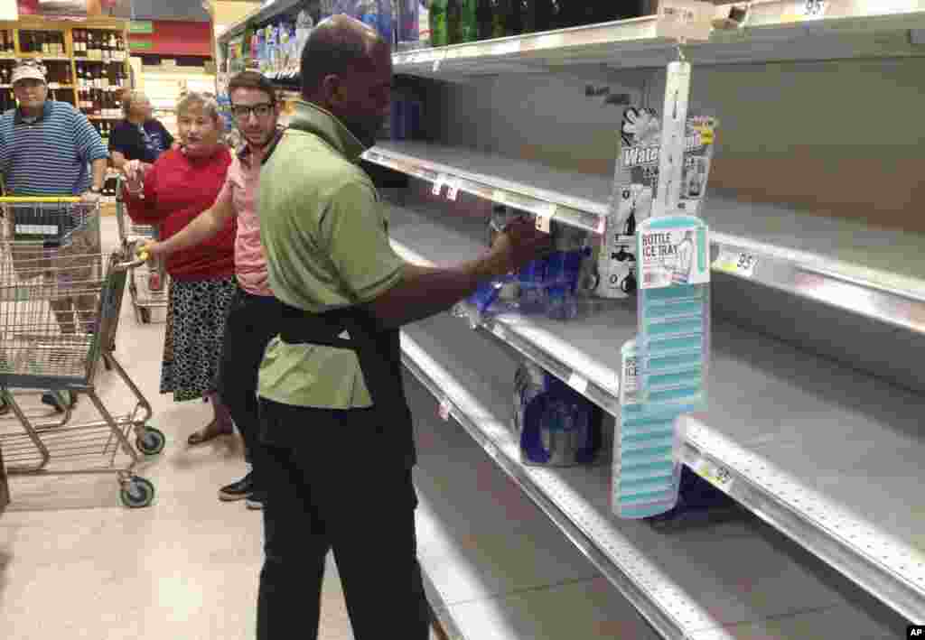 Un empleado de una tienda de la cadena de supermercados Publix en Surfside, Florida, vuelve a colocar paquetes de agua embotellada en los estantes del establecimiento, &nbsp;que han quedado vacíos por la demanda del público que realiza preparativos antes de la llegada del huracán Irma. AP Sept. 6, 2017.