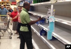 Un empleado de la cadena de supermercados Publix vuelve a llenar con botellas de agua los estantes vacíos en Surfside, Florida. Septiembre 6, 2017.