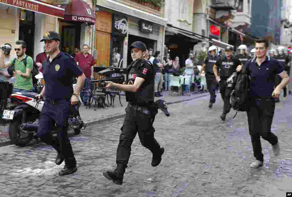 Turkish police, one holding a rubber bullet rifle, center, run to disperse participants of a Gay Pride event in support of Lesbian, Gay, Bisexual and Transsexual (LGBT) rights in Istanbul.