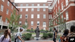 Estudiantes en la Unviersidad Georgetown en Washington, D.C., pasan frente a una estatua jesuita.
