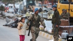 A soldier helps a girl to cross a street after an earthquake in Ercis, Turkey October 24, 2011.