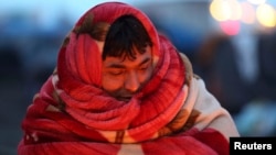 Một người di dân Afghanistan quấn chăn quanh người để giữ ấm trước khi bị cảnh sát Pháp sơ tán khỏi một trại được dựng tạm ở Calais, miền bắc Pháp. 