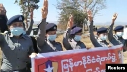 Полицейские с транспарантом салютуют, присоединившись к протесту против военного переворота в Мьянме
