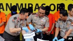 Indonesian Deputy National Police Chief Muhammad Syafruddin, center, checks huge quantities of suspect confiscated alcohol during a press conference in Jakarta, Indonesia, Wednesday, April 11, 2018.