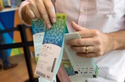 FILE - In this June 20, 2016, file photo, a man handles the Olympic tickets he just purchased at a shopping mall in Rio de Janeiro, Brazil. Tokyo Olympic organizers launched their ticket website on Thursday, April 18, 2019.